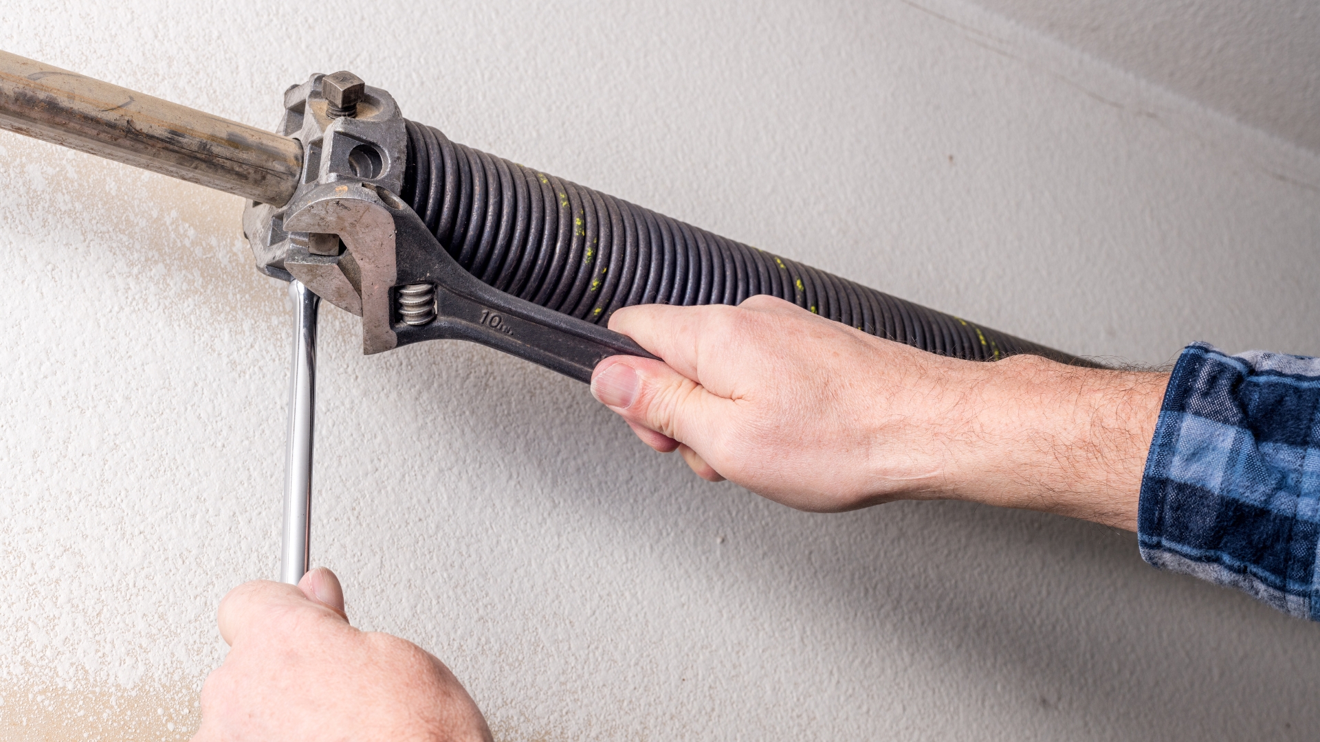 Garage door technician tightening a torsion spring during a repair.