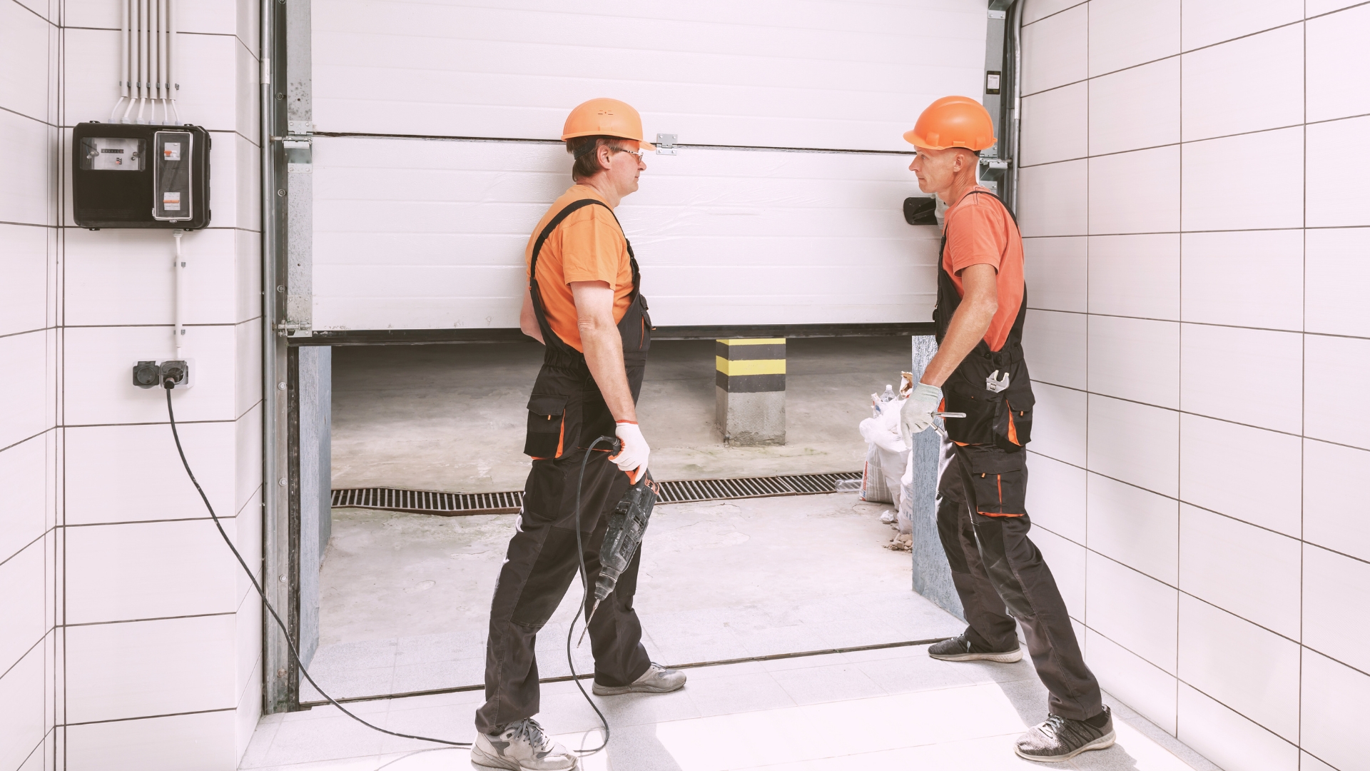 Two technicians performing professional garage door installation in a commercial garage