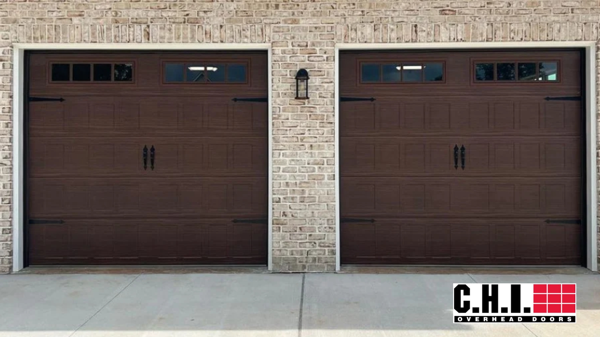 Newly installed dark brown garage doors from C.H.I. Overhead Doors featuring top windows and classic carriage-style accents