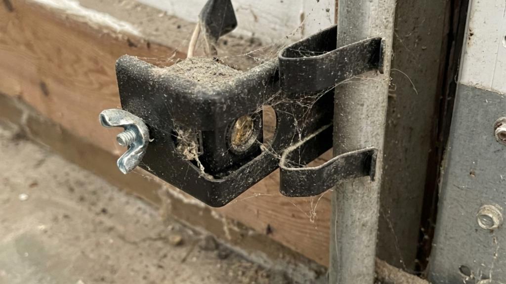 Dirty garage door sensor covered in cobwebs preventing the door from closing